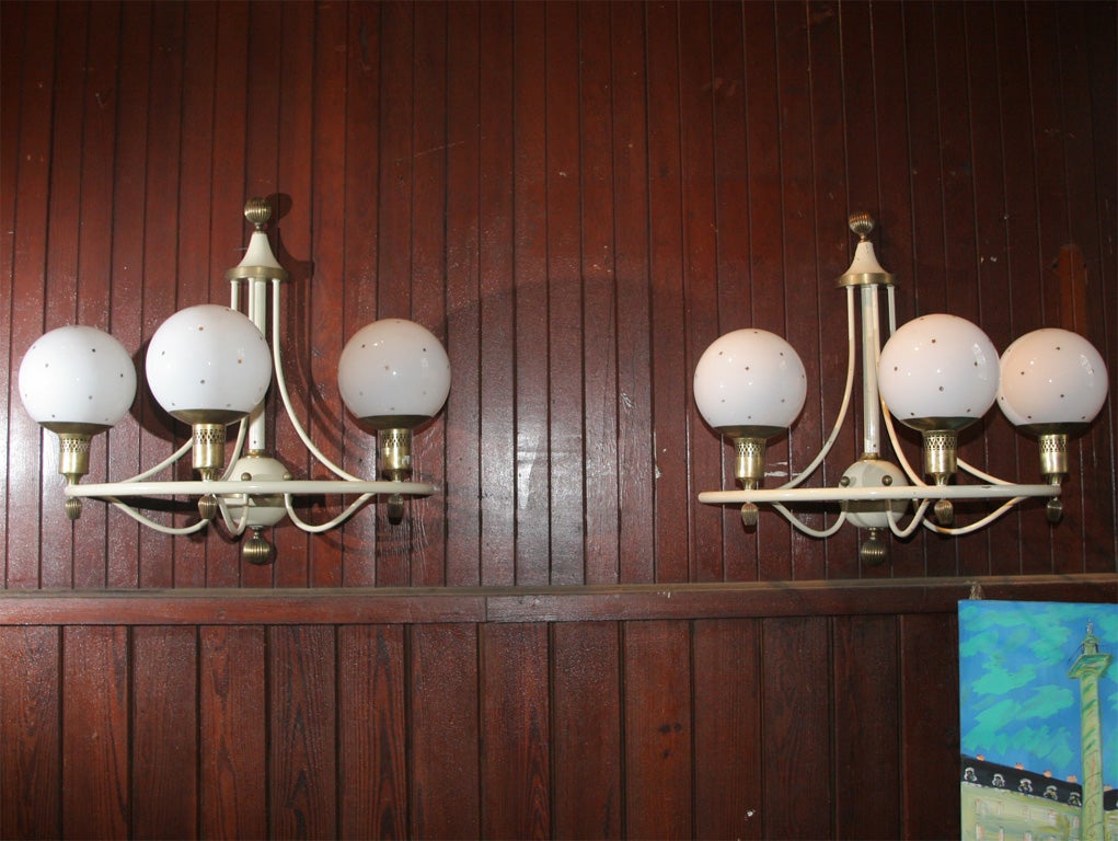 Tubular metal and brass trimmed sconces with large gilt star decorated glass globes.