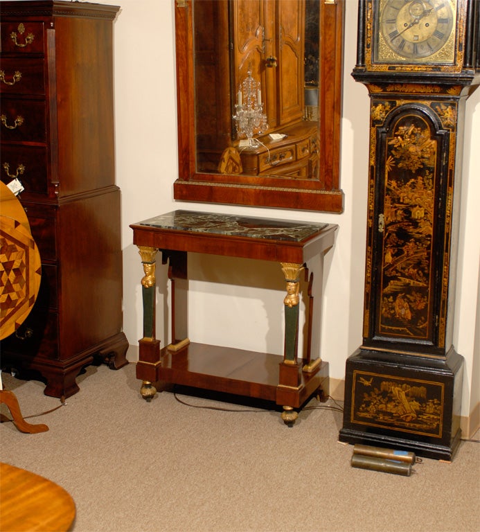 An Empire Period mahogany console table of small size.  The rectangular top inset with a white and green variegated marble top and the frieze inset with a drawer and flanked by painted and gilt upright supports headed by female figures. The console