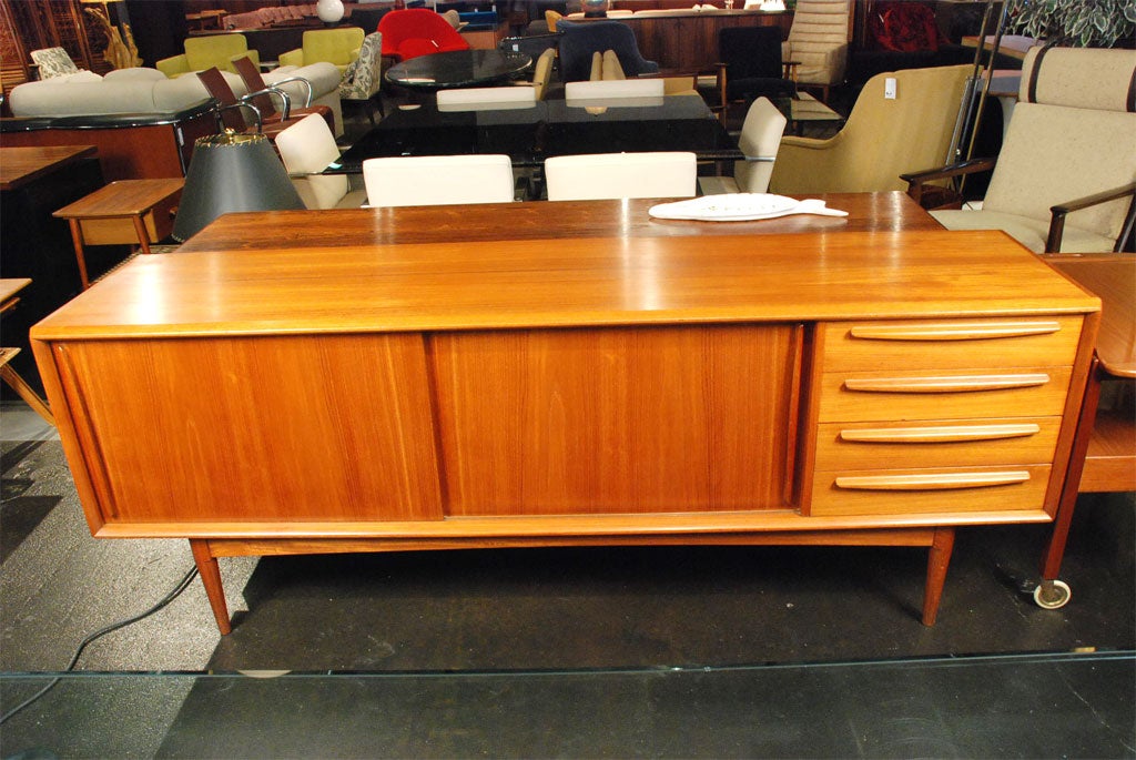 This beautifully detailed Danish modern sideboard boasts exceptional craftsmanship. On the right side, sliding doors reveal small drawers and shelves, and on the left the four large drawers offer plentiful storage.