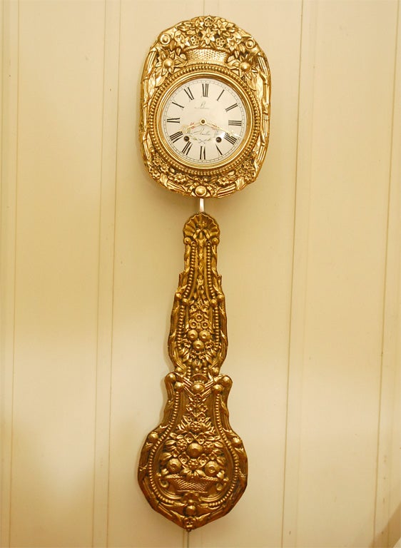 Period French regional Morbier clock with embossed brass face and large pendulum. Hand painted metal face with the name Ledoux Plouillac, 06'. Wood back with metal sides and access doors to clock works. Interior and works restored to perfect working