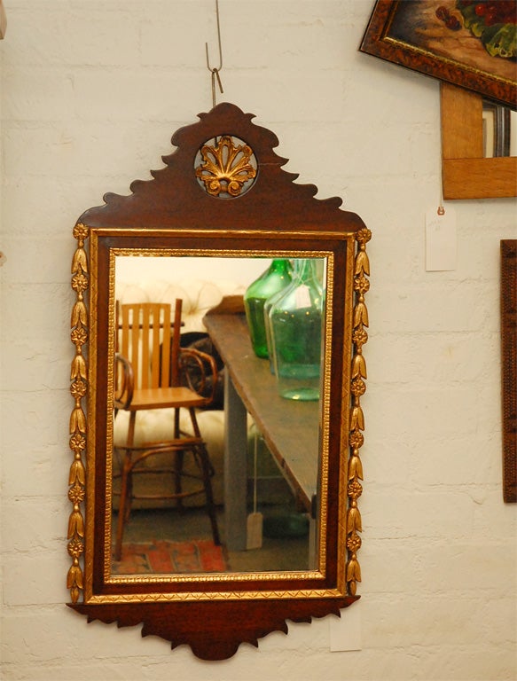 This mirror is considered to be a 19th century piece made in the Georgian style. The frame shows good surface oxidization on the back and appears to be carved mahogany having gilt elements. Undulating and symmetrical the shape proves to be very