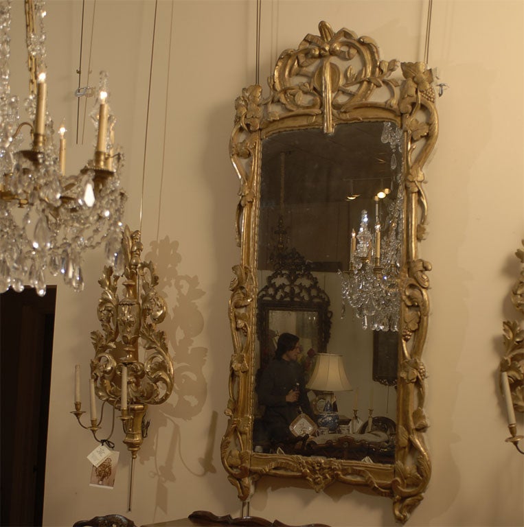 Ein großer Louis XV-XVI Spiegel im Übergangsstil mit cremefarbenem und vergoldetem Rahmen. Sie stammt aus dem dritten Viertel des Jahres 1700 und ist französischen Ursprungs.

Der Spiegel von imposanter Größe und mit fein geschnitzten Scroll &
