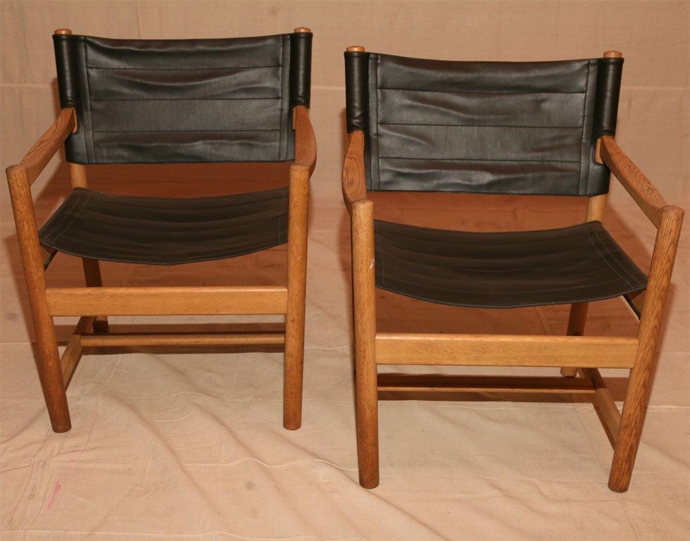 Pair of black leather an oak frame armchairs with leather strap in back, 
Danish mid-20th century modern by Danish designers Ditte and Adrian Heath.