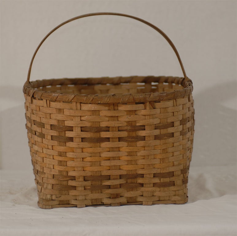 A very nice sized basket still retaining good coloration of the vegetable dyed splints. Nice pattern and weaving; split oak handle.  Cherokee, North Carolina.