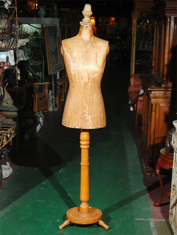 C. 1920 European dress form/mannequin on a wood stand. The main torso is made of a hard paper mache, and it's mounted on a tall wooden stand with 3 legs, and a wood finial at the neck area. These hard to find pieces are always great props in store