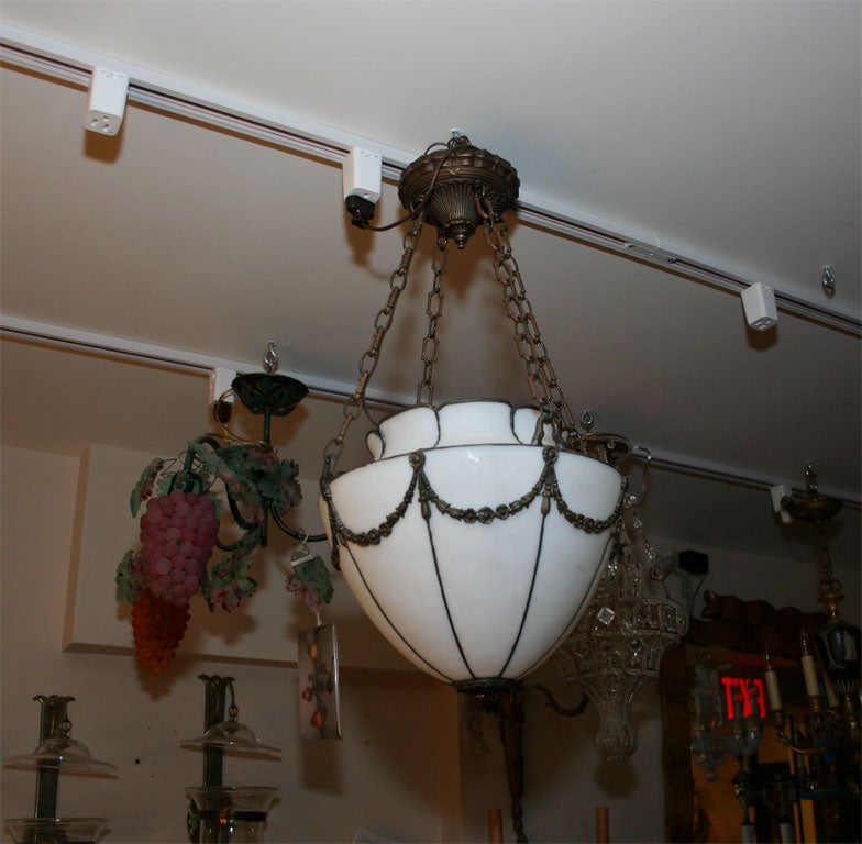 An American leaded slag glass ceiling light with draped bellflower motif. The vase shaped body suspended from four lengths of bronze chain and canopy.