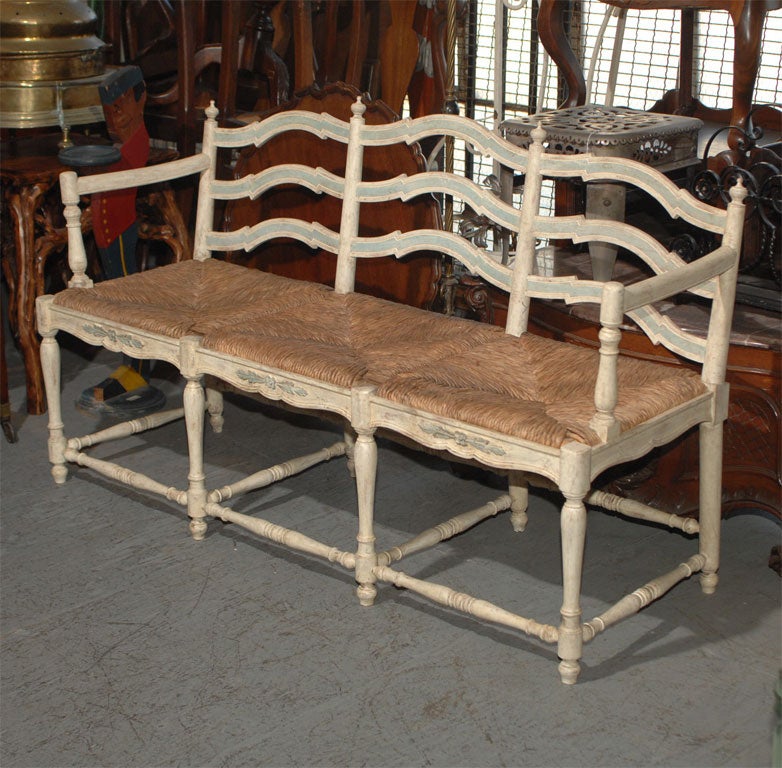 Decorative carved and painted three seater bench with rush seat in the 18th century style. White with pale blue paint.