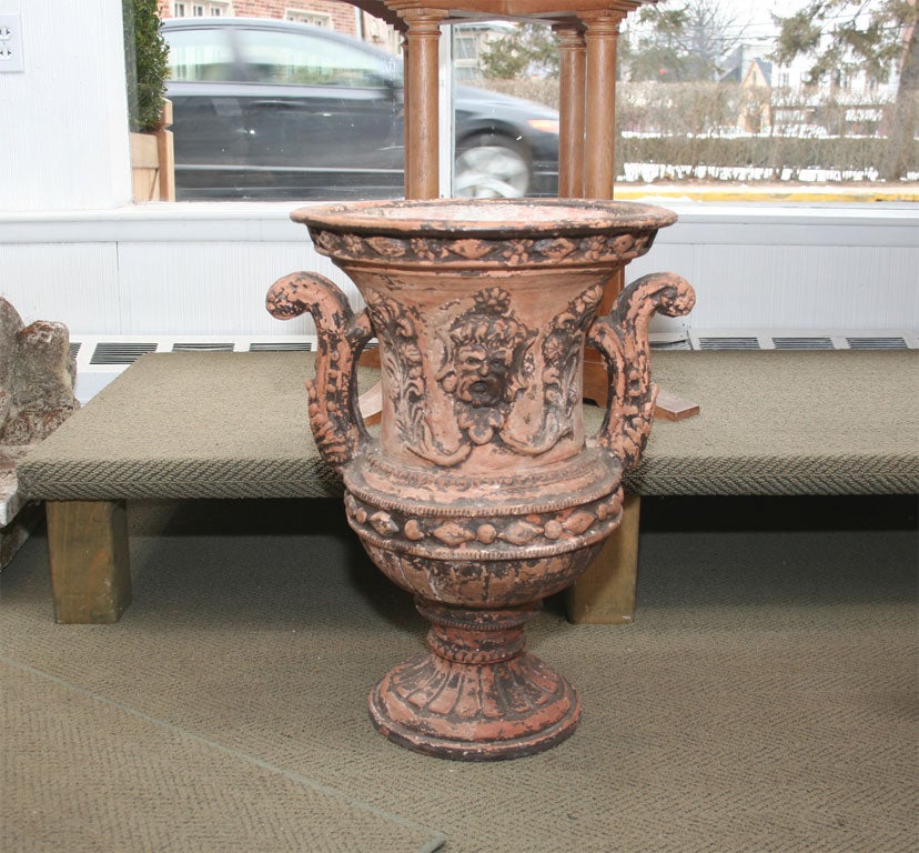 An ornate pair of urns with mask & foliage design