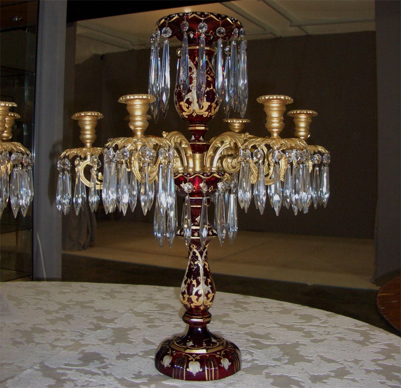 This is a spectacular pair of Bohemian handblown ruby crystal six-arm candelabra with bronze doré bobeches and hanging prisms, 19th century. They are decorated with raised enamel and gold with bronze mounts. Large and dramatic, these are the perfect