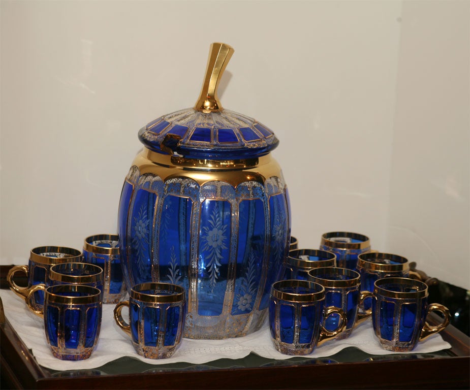 Beautiful hand blown cobalt overlay and panel cut to clear punch bowl with matching lid, wheel cut floral decoration and gold trim. 12 matching handled punch cups to complete this wonderful set.