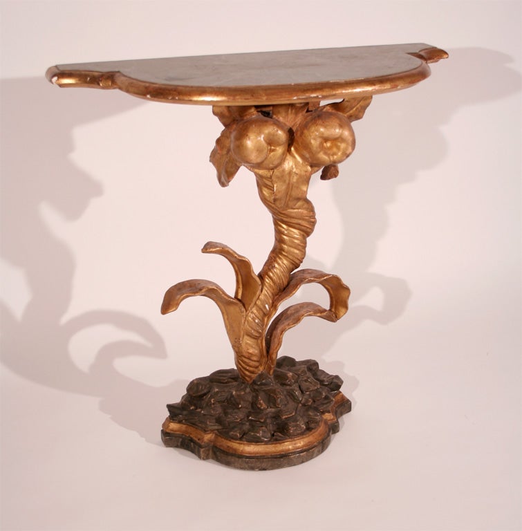 An Italian Rococo giltwood and painted console with palm and rocaille motif with faux green marble top.