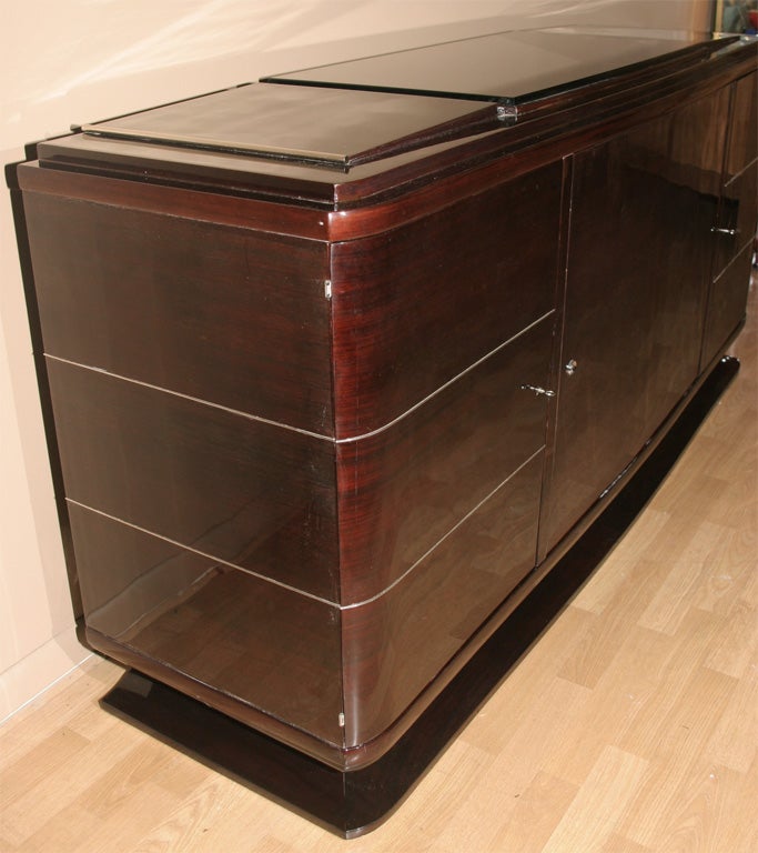 Magnificent sideboard of Rio palissandre with original black opaline top. Two side doors reveal shelves and drawers. Center door reveals adjustable shelves for ample storage.