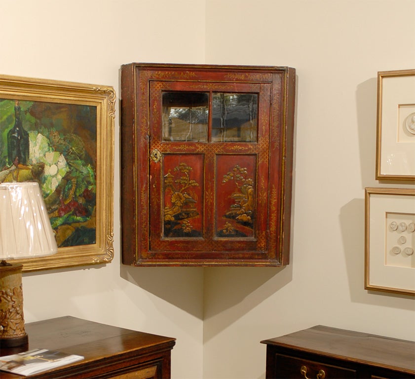 This is a fabulous Hanging Red Chinoiserie Cupboard.  The cupboard has a 2 paneled single door with Chinese scenes.  The top of the single door has 2 windows with original glass.  Inside are 2 shelves.  The top shelf that can be seen through the