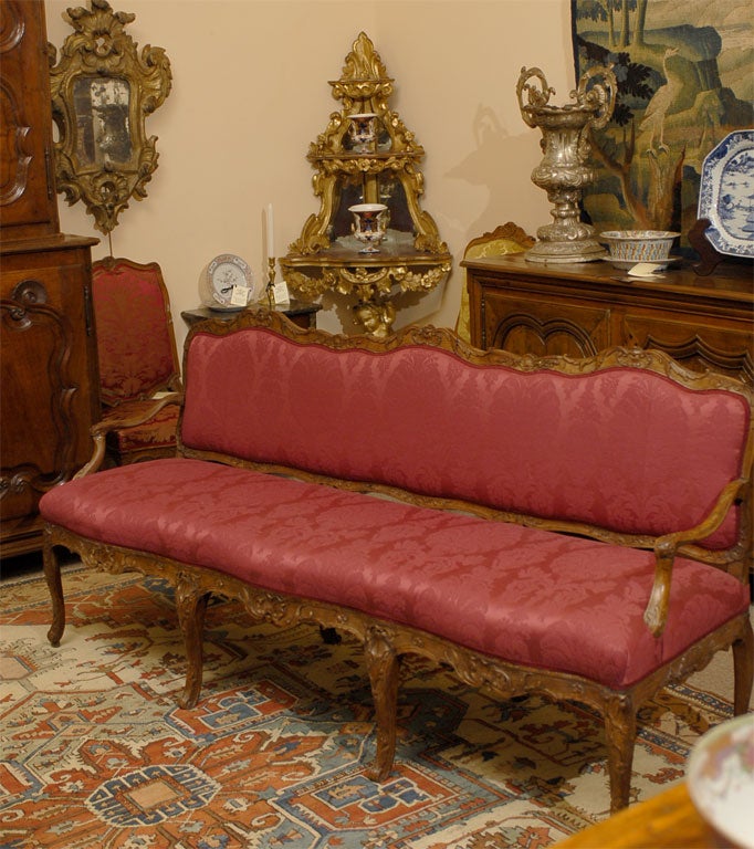 A fine early Louis XV period Canape, with crisp carved designs throughout the exposed beechwood frame, and with upholstered seat & back flanked by open arms in meandering form.

The back with serpentine apron featuring carved designs and moulded