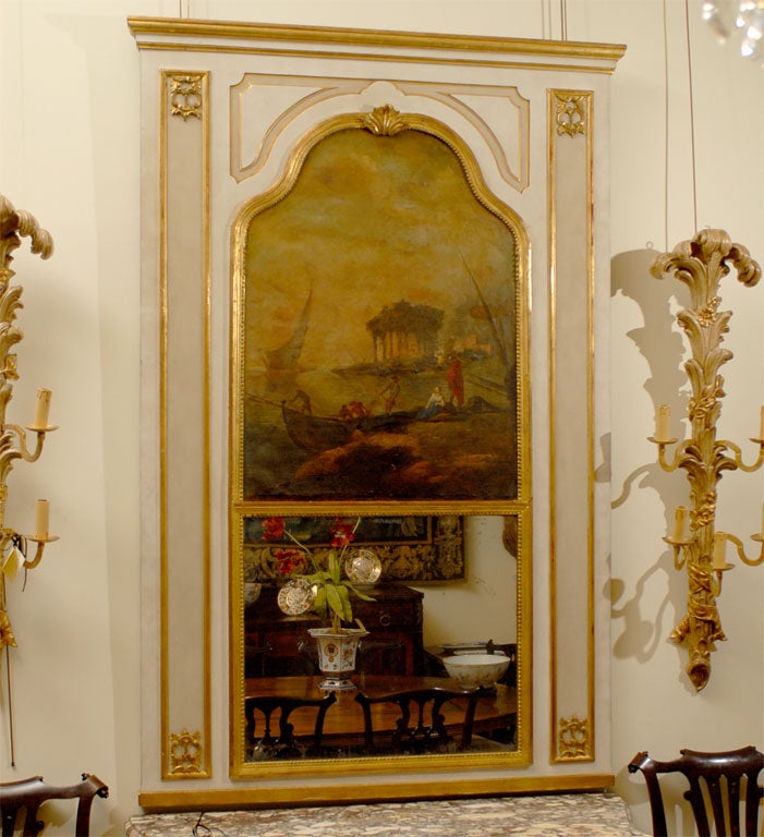 A Louis XVI style trumeau Mirror with Oil-on-canvas painted scene. Dating from the third quarter of the 1800s, and originating in France. 
The mirror frame with tan & cream painted grounds, and accented by gilt borders throughout. the upper section