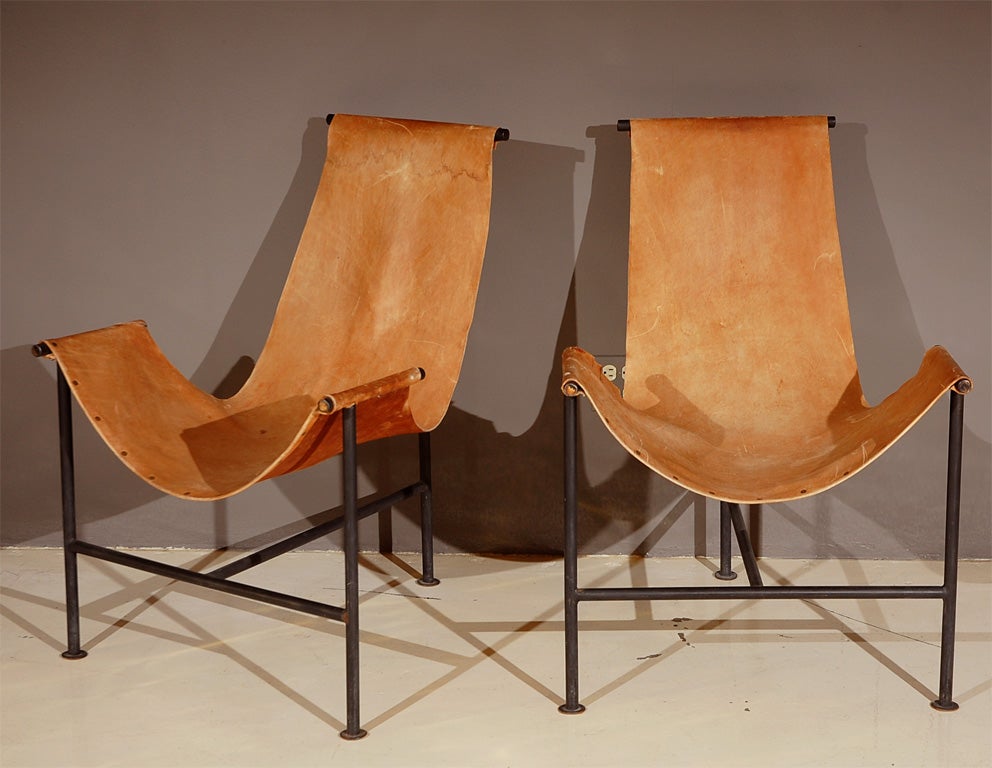 Sculptural pair of leather sling chairs on iron frames.