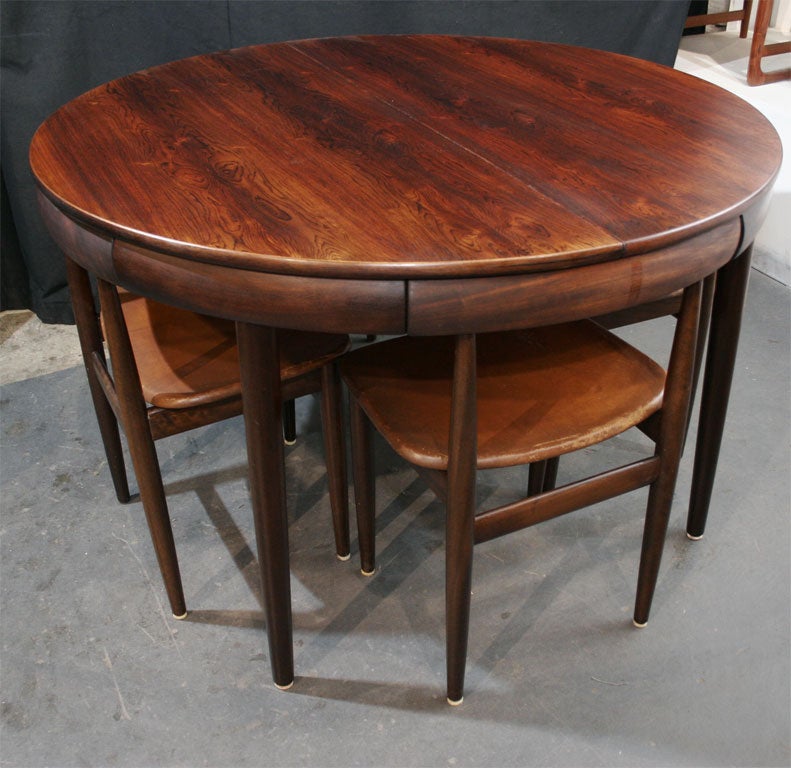 Fine example of this hard to find rosewood dining table with nested dining chairs by Hans Olsen.  This version has the four legged chairs and a butterfly leaf.  The chairs have their original cognac leather upholstery.