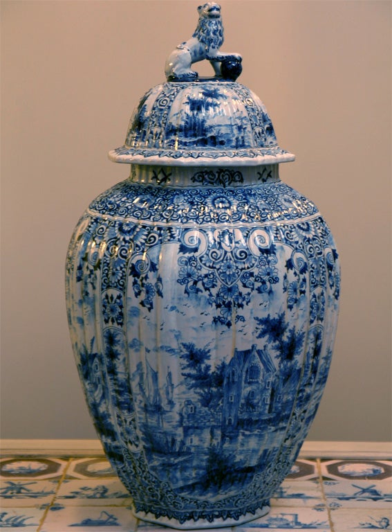 A pair of rare large-scale covered Dutch Delft vases with figures in a landscape. Each cover has a finial in the form of a rampant lion with an orb.