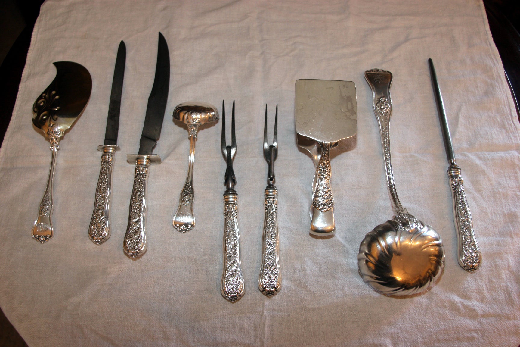 An exquisite set of antique Tiffany sterling silver serving pieces in the Olympian pattern. Comprised of 1 gravy ladle, 1 pair asparagus serving tongs, 2 large serving spoons, a 3-piece roast serving set, 2 serving forks, 1 fish server (vermeil