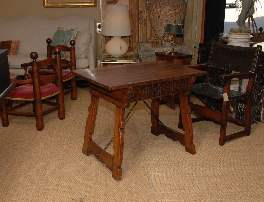 The rectangular top above a single frieze drawer applied with iron pull, raised on splayed square fluted A-forn end standards united to the underside of the top by slender elongated baluster wrought-iron braces.