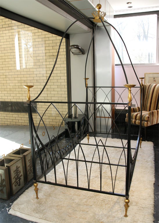 Campaign-style daybed in wrought iron with gilt details, including a cup on each of the four posts and tapering feet. Removable curved canopy top with gilt crown finial. To fit a mattress measuring 40 1/4 x 80 inches. Ilustrated in Erica Brown's