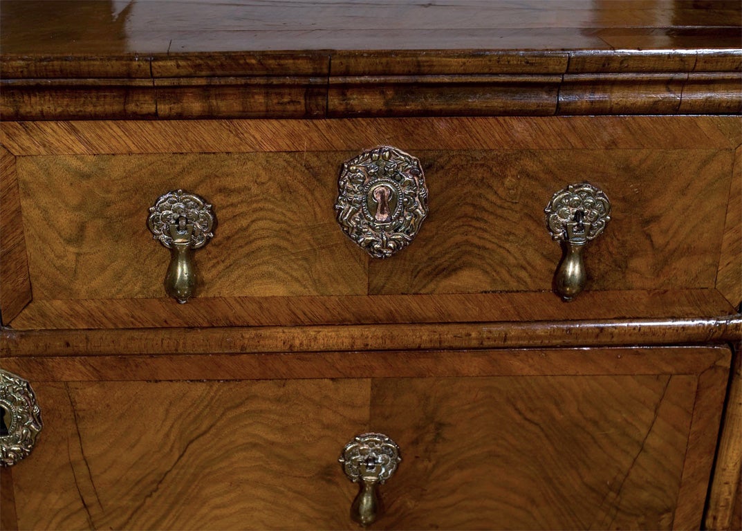 A beautifully proportioned small scale English, walnut five-drawer chest with inset self-band on top and crossbanded drawer fronts; supported on bracket feet. Brass teardrop pulls with foliate backplates and matching escutcheons complete the look of