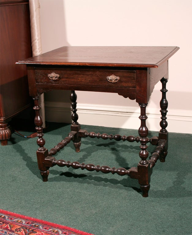 Oak lowboy has turned legs and stretchers, pegged construction, shaped apron on front and sides, cast and tooled original brass handles.  Molded top, original finish.