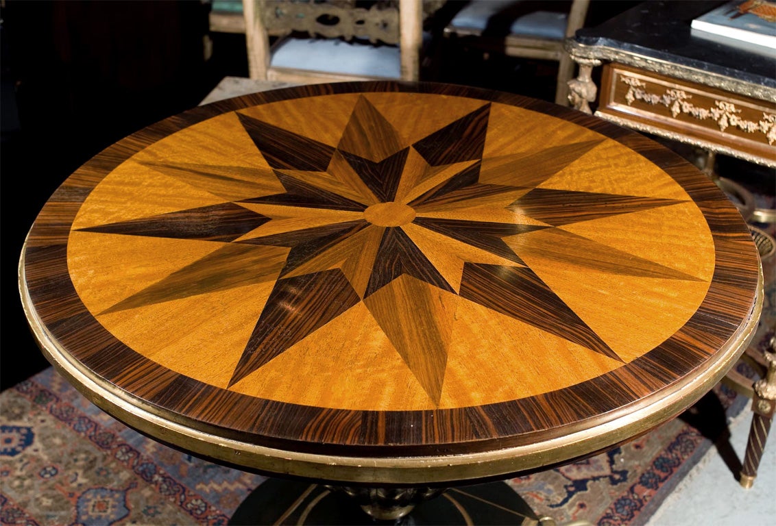 Regal mahogany and Macassar ebony round centre hall table with intricate starburst inlaid top, sitting on ebonized and gilded stand, raised on solid gilt bronze claw feet. Provenance Christies NY.