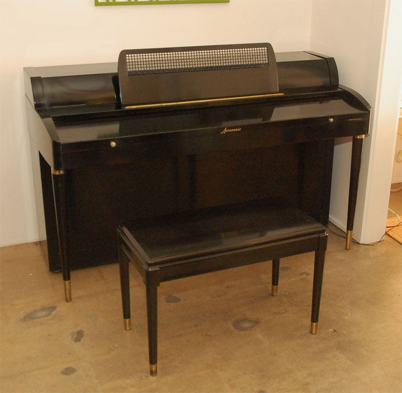 1950’s black Acrosonic piano with brass trim on legs was built by Baldwin.  The music stand has an intricate basket weave design.  Matching bench. Recently tuned and polished.
