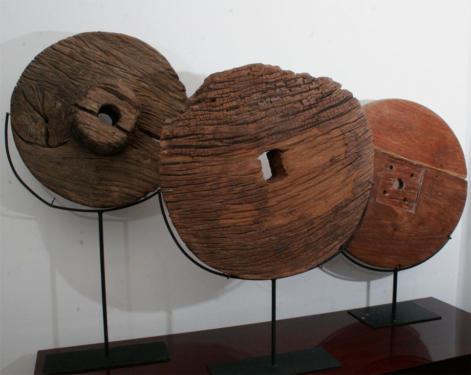 A collection of Thai ox cart wheels on metal stands.