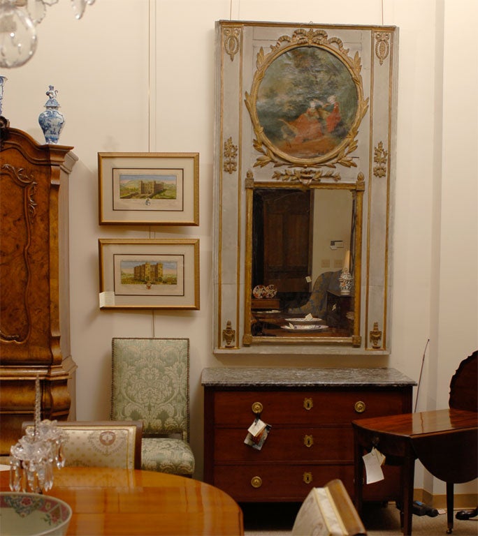 Grand miroir Trumeau d'époque Louis XVI, présentant une scène pastorale bien peinte, alignée au-dessus de la plaque de miroir rectangulaire. Le cadre présente un fond peint en crème accentué par des motifs dorés en relief dans le goût néoclassique.