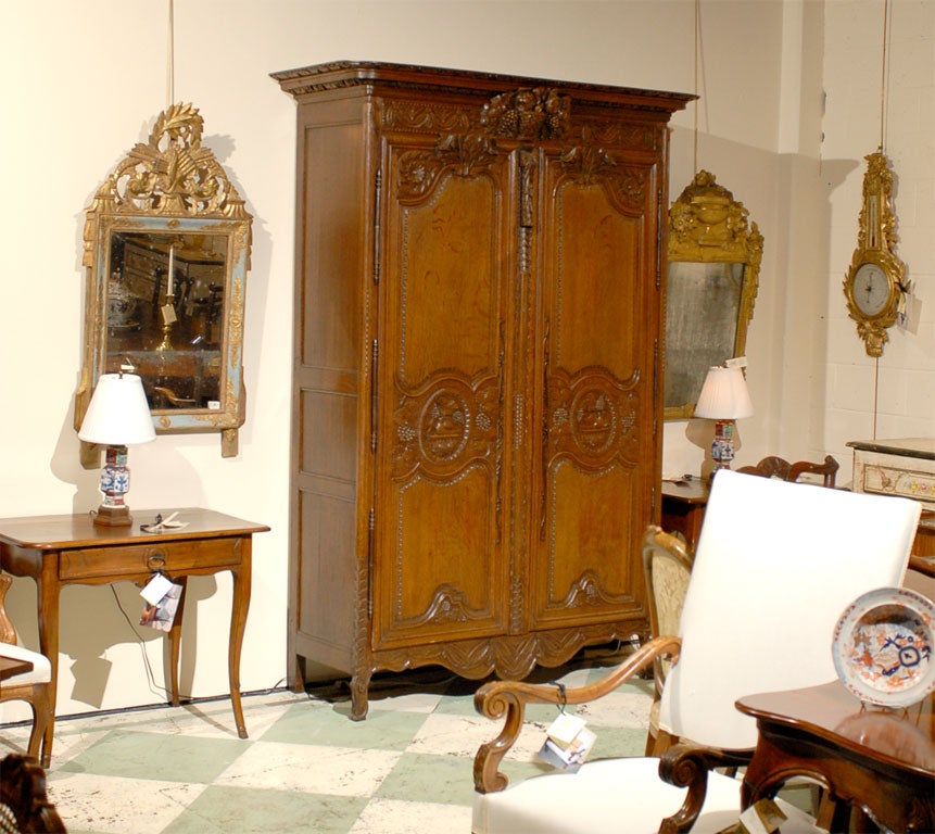 A Louis XV Carved Oak Armoire, originating from Normandy France during the second half of the 18th Century.

The case consists of a carved frieze and paneled doors above a shaped apron, all resting atop cabriole feet.  

Most notable is the top
