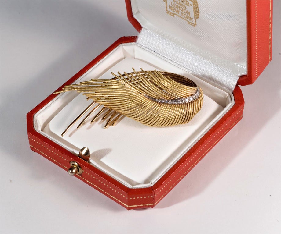 Cartier wing-like designed brooch in original box; 18kt gold and diamonds. This elegant and timeless brooch reveals the unique quality and workmanship of its maker.