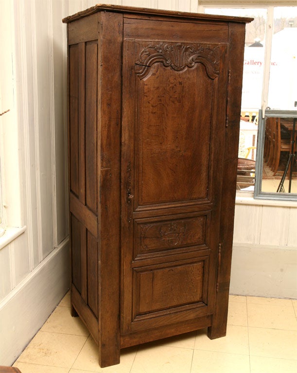 Fine example of rustic Louis XIV and Louis XV transitional  style single door cupboard w/hand carved shell motif.  Original hardware.  Some lost of wood detail at the upper left side of the crown. iron escutcheon. Ask us about adding shelving, etc.