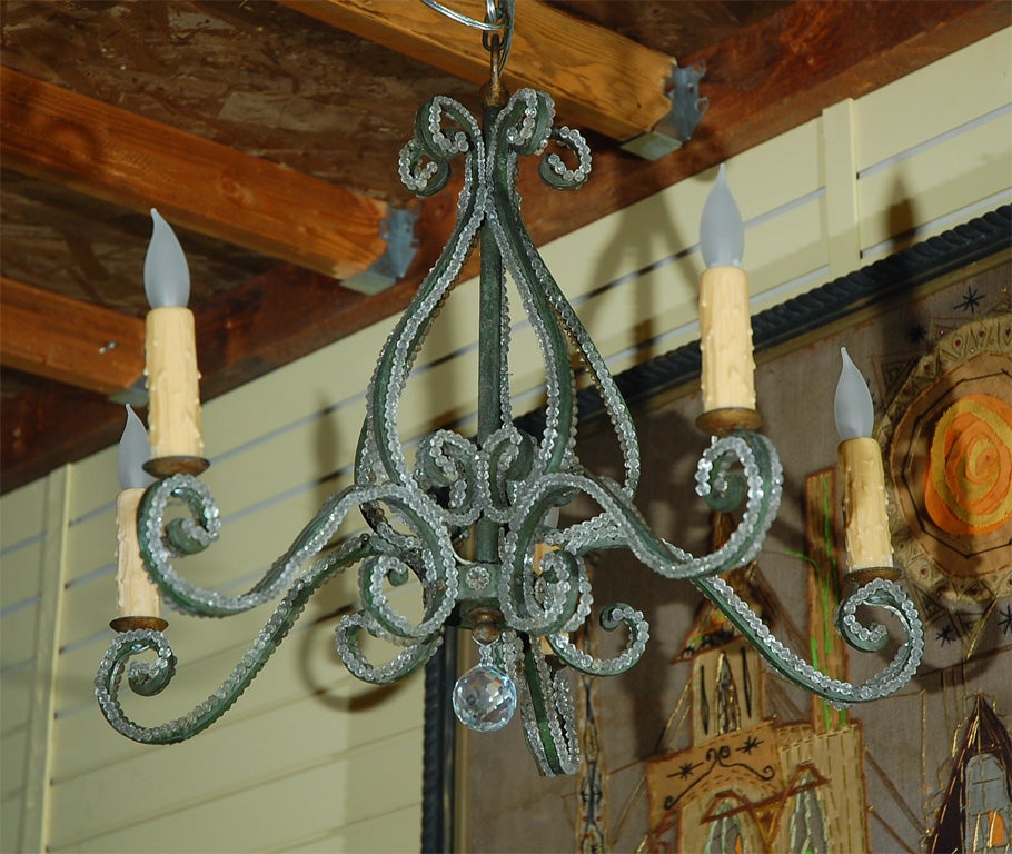 Four bulb wrought iron chandelier accented with crystal beading 
( typical of Maison Bagues chandeliers). Large round crystal hangs from center.