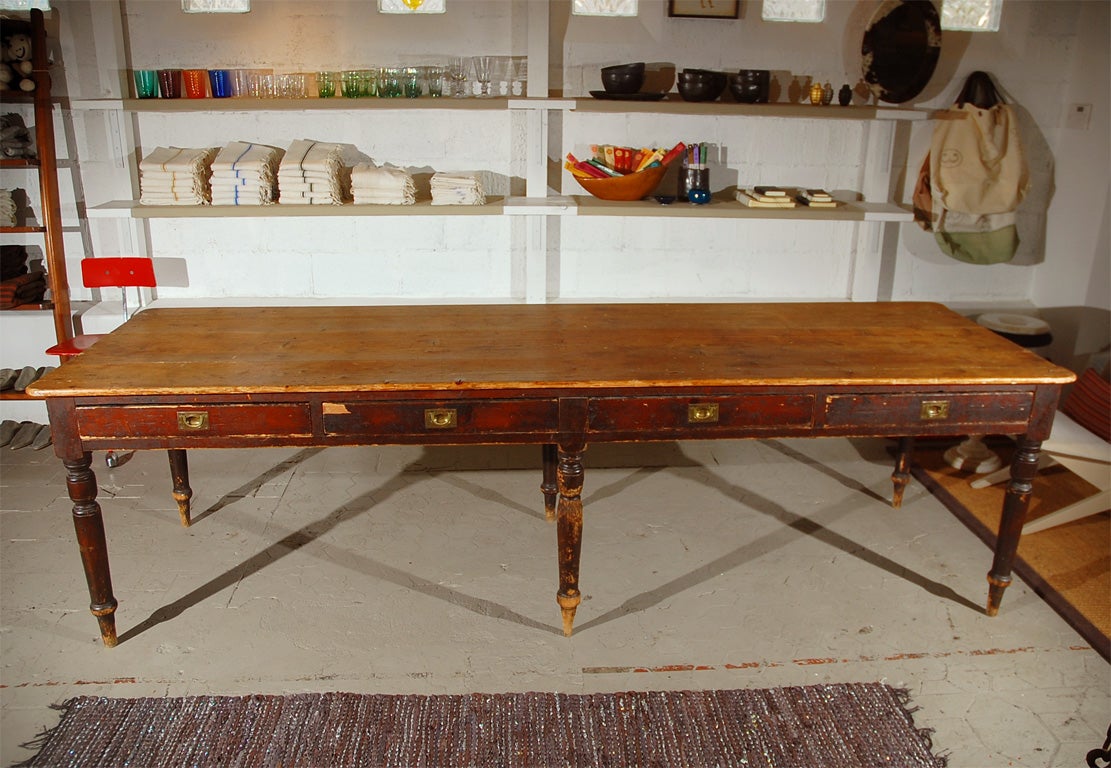 A stunning and handsome antique English writing table from the early 1900's. Gorgeous mahogany with six very sturdy turned wood legs and a beautiful well-crafted wood plank top and four dovetail drawers with lovely original inset brass pulls. From