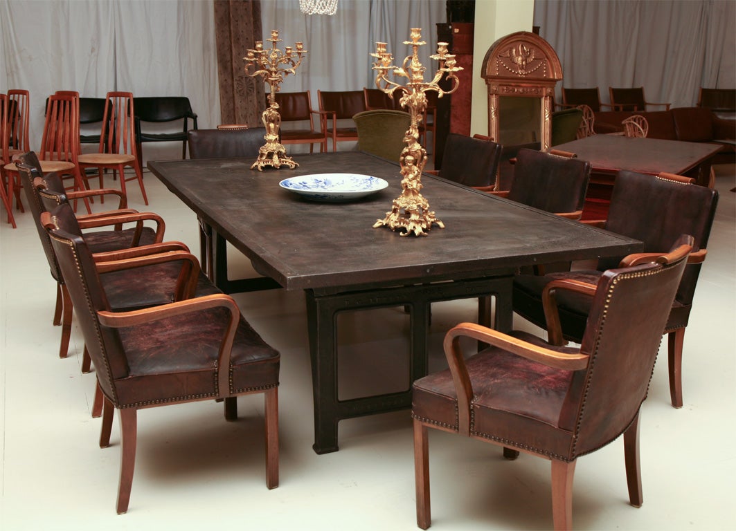 Set of 8 leather and walnut dining room chairs from 1920's together with an industrial table made from a 19th century iron base and contemporary metal top, hand beaten.   Table measures 97 x 39w x 30h.  Chairs: 35h x 25w x 22d x 18 seat ht.  Chairs