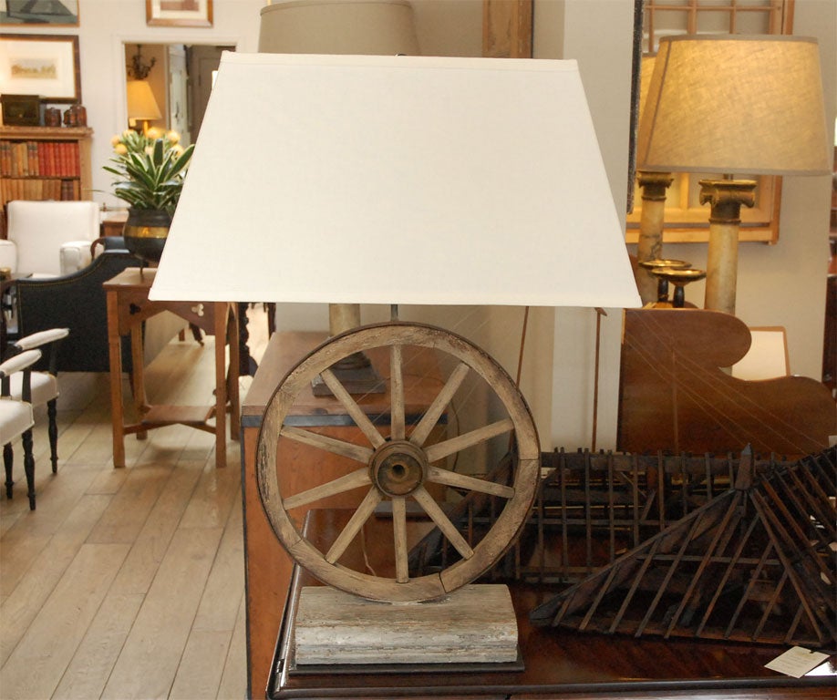 A rustic element lamp from a wood and iron “wagon” wheel with a custom linen shade. Pair of lamps while available.