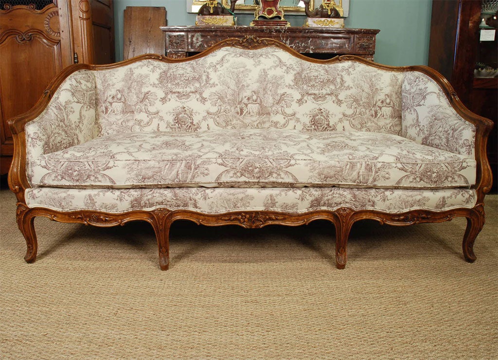 French Louis XV style carved walnut sofa, with nice floral cartouche and crest rail detailing, cabriole legs.  Newly-upholstered in French linen toile, down-stuffed cushion.