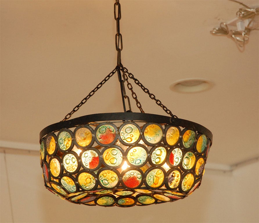 Beautiful iron chandelier with individual stained glass slag circles.  One of a kind, probably handcrafted . Gorgeous when illuminated.