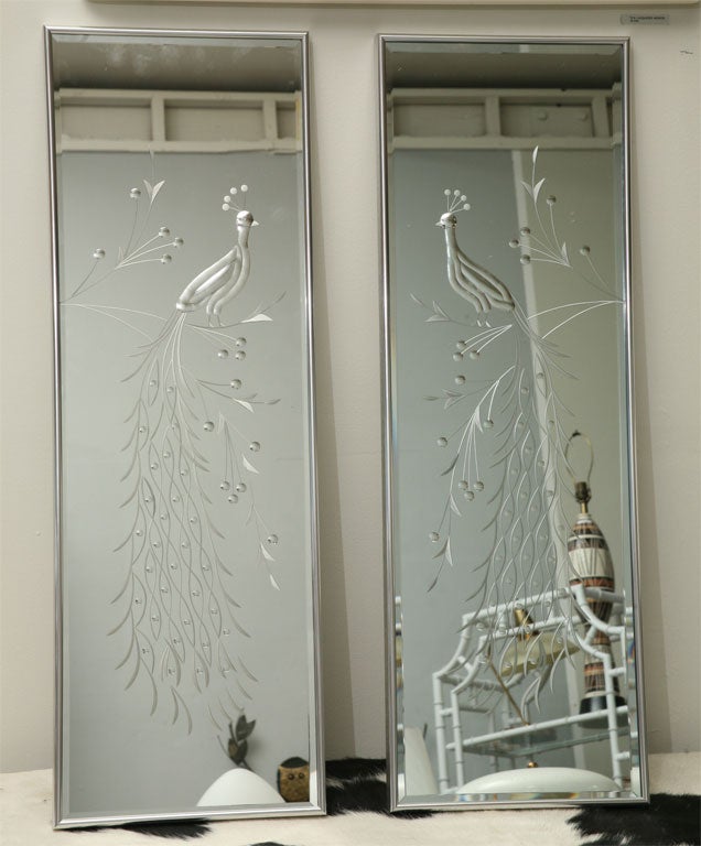 Glamorous pair of 50's mirrors feature hand-etched, extravagantly long-tailed, peacocks (right and left opposing). Up-dated in the 70's with simple chromed frames.