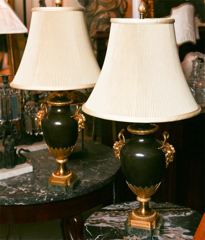 A very finely made pair of bronze and gilded urns which have now been made into lamps. The bronze casting is finely chassed and the gilding orginal as are the fitted antique marble bases. The shades are in a good pleated silk from about 20 years ago.