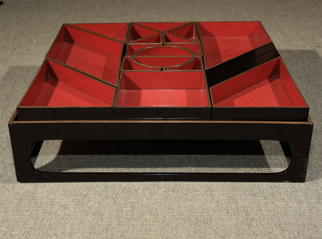 A Japanese lacquered wood bento, food container, of unusual geometric design resembling a tangram.  The bento consisting of seventeen red lacquered geometric food containers of various shapes and two boxes for chopsticks under a two piece lid and
