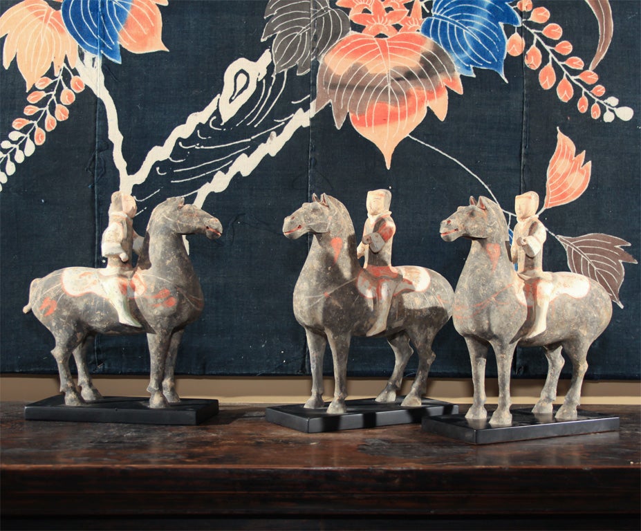 Chinese clay models of horse and riders. Each horse standing four square with head high with a straight backed mounted warrior holding his arms extended to hold the reins as if in formal parade formation. The whole unglazed but with original