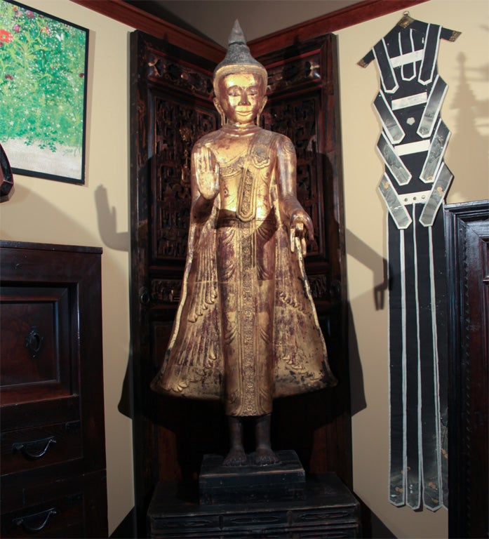 Exceptionally large Burmese dry lacquer statue of Buddha. Standing on a wood plinth base, the figure depicted with right hand in abhaya mudra symbolizing an absence of fear; the left hand in vitarka mudra, symbolizing seal of reasoning. The head