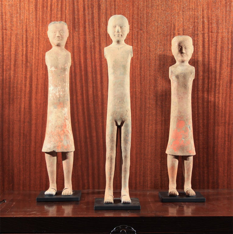 Chinese earthenware burial statues. The tall figures with slender legs and individually modeled faces. With two holes at the shoulders where wood arms would have originally been attached. Such figures were buried with members of the nobility and