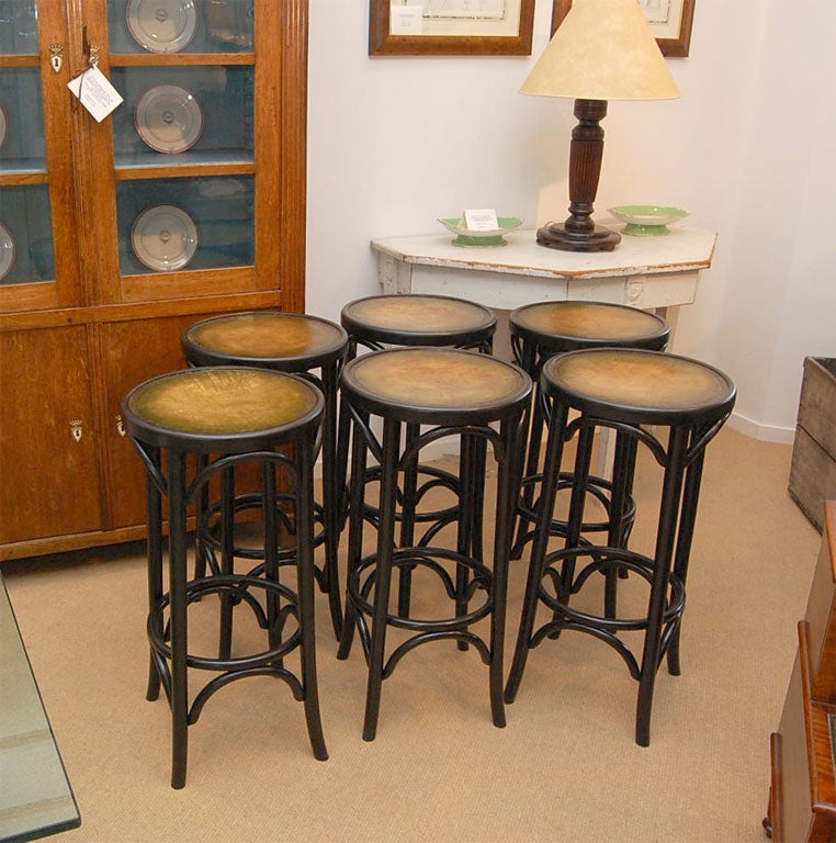 A set of three 1930's Bentwood Bar Stools from an English pub repainted in an ebonized finish with new antiqued green leather insert seats.  Can be purchased separately for $1,200.