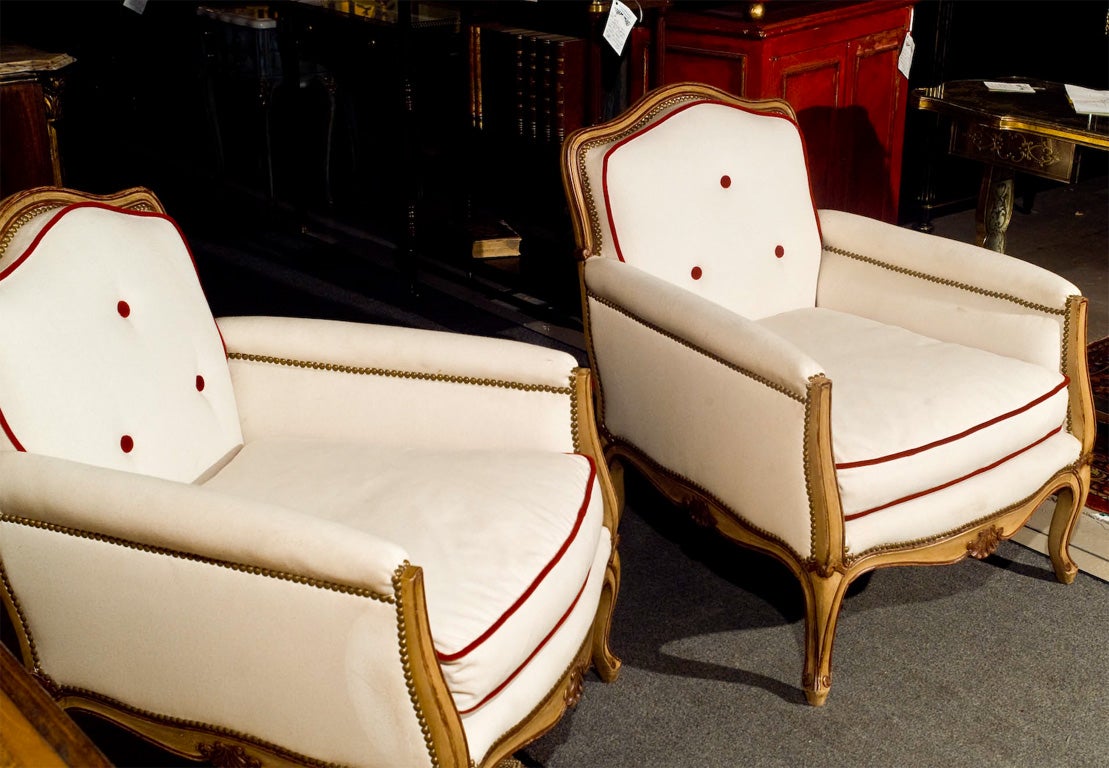 Pair of Jansen Stamped Hollywood Regency Louis XV Style Bergere Lounge Chairs. This fine Pair of Jansen stamped bergere chairs, upholstered in white linen with red piping and buttons. Fine distressed finish. Louis XVI style. Red hi lights to match