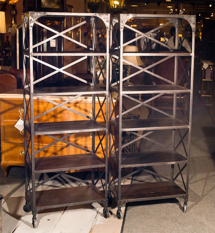Industrial pair of cross back metal etageres. Each with six solid oak wood shelves. Both on Casters. Can buy one. PLEASE VISIT OUR FACILITY, GREENWICH LIVING ANTIQUES CENTRE, FOR A NEVER-ENDING SHOPPING EXPERIENCE FOR HIGH-END ANTIQUES.