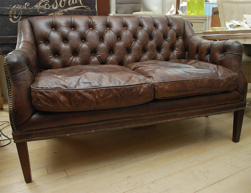 Small scale tufted leather, nicely aged with nailhead dtail on plain dark wood legs